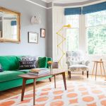 Žalia sofa skandinaviško stiliaus gyvenamajame kambaryje